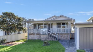 Une maison de plain-pied avec un porche, un petit jardin devant et une enseigne indiquant « The Beach House 23 ».