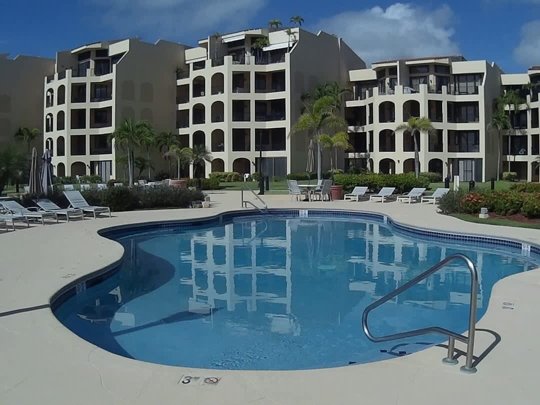 Ein Swimmingpool mit Liegestühlen und ein mehrgeschossiges Gebäude im Hintergrund.