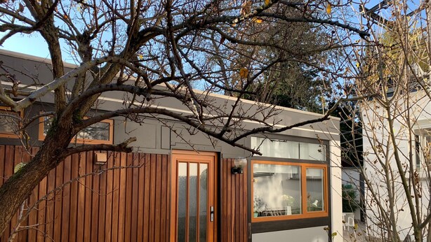 A modern house with a wooden exterior, a glass door, and a small garden area. - Cozy 2 room apartment in Mainzer Bestlage (Oberstadt)