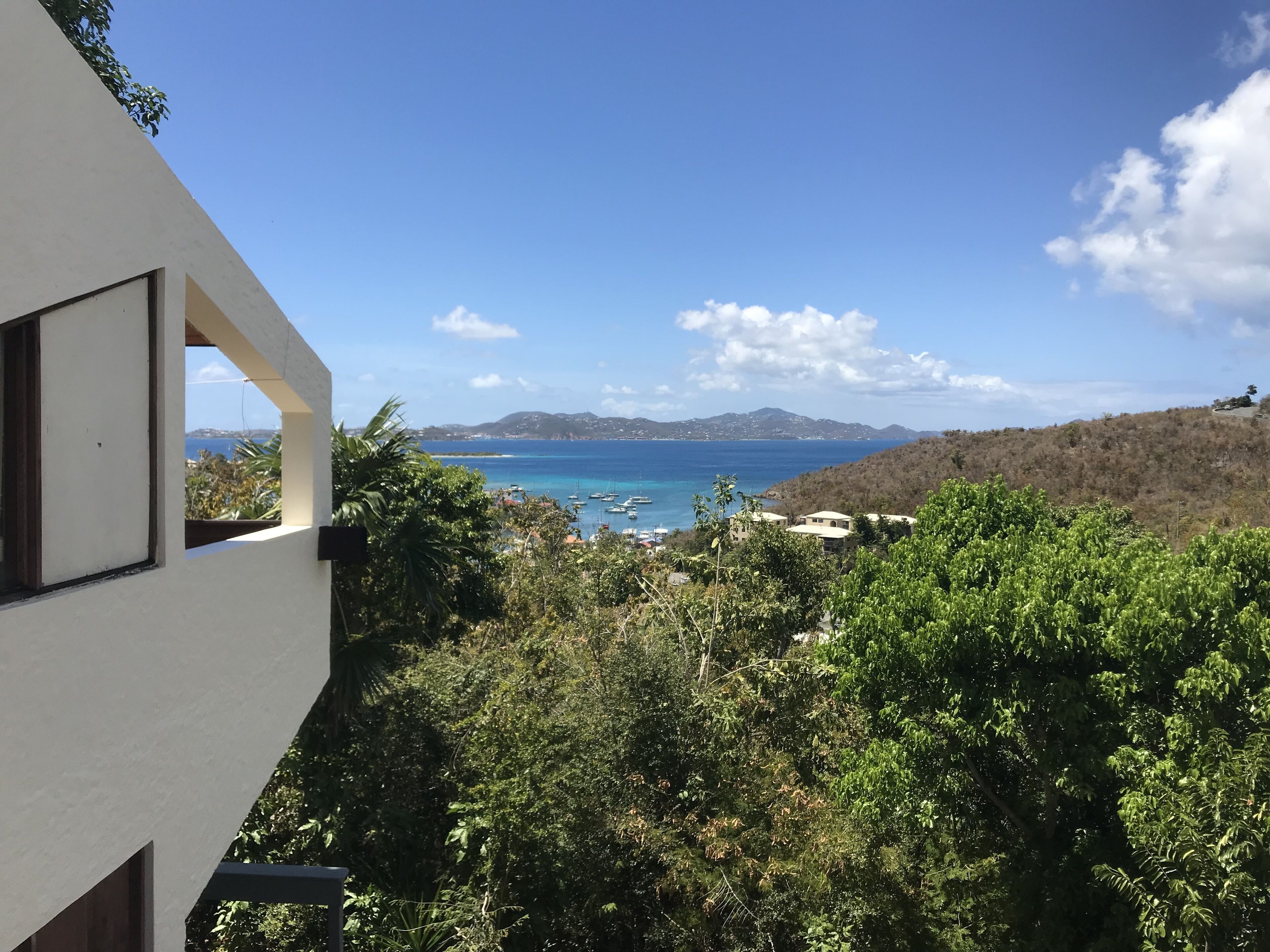 A coastal view with a clear sky, a body of water, and a hilly landscape.