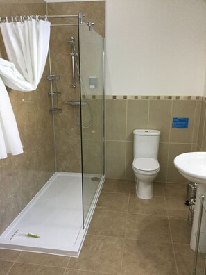 Un baño con ducha de vidrio, inodoro y lavamanos.