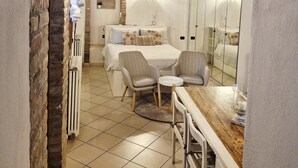 A bedroom with a bed, two chairs, a small table, and a mirror. - In the ancient Jewish ghetto (Ferrara)