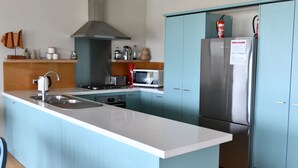 Una cocina moderna con una isla central, electrodomésticos de acero inoxidable y armarios color turquesa.