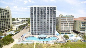 Ett hotell med en stor pool i mitten, flera balkonger och utsikt över de omgivande byggnaderna.