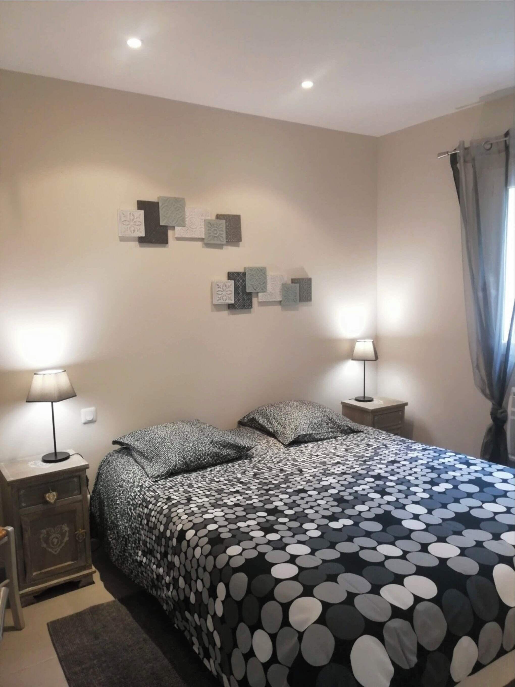 A bedroom with a bed, two bedside tables, a dresser, and wall decor.