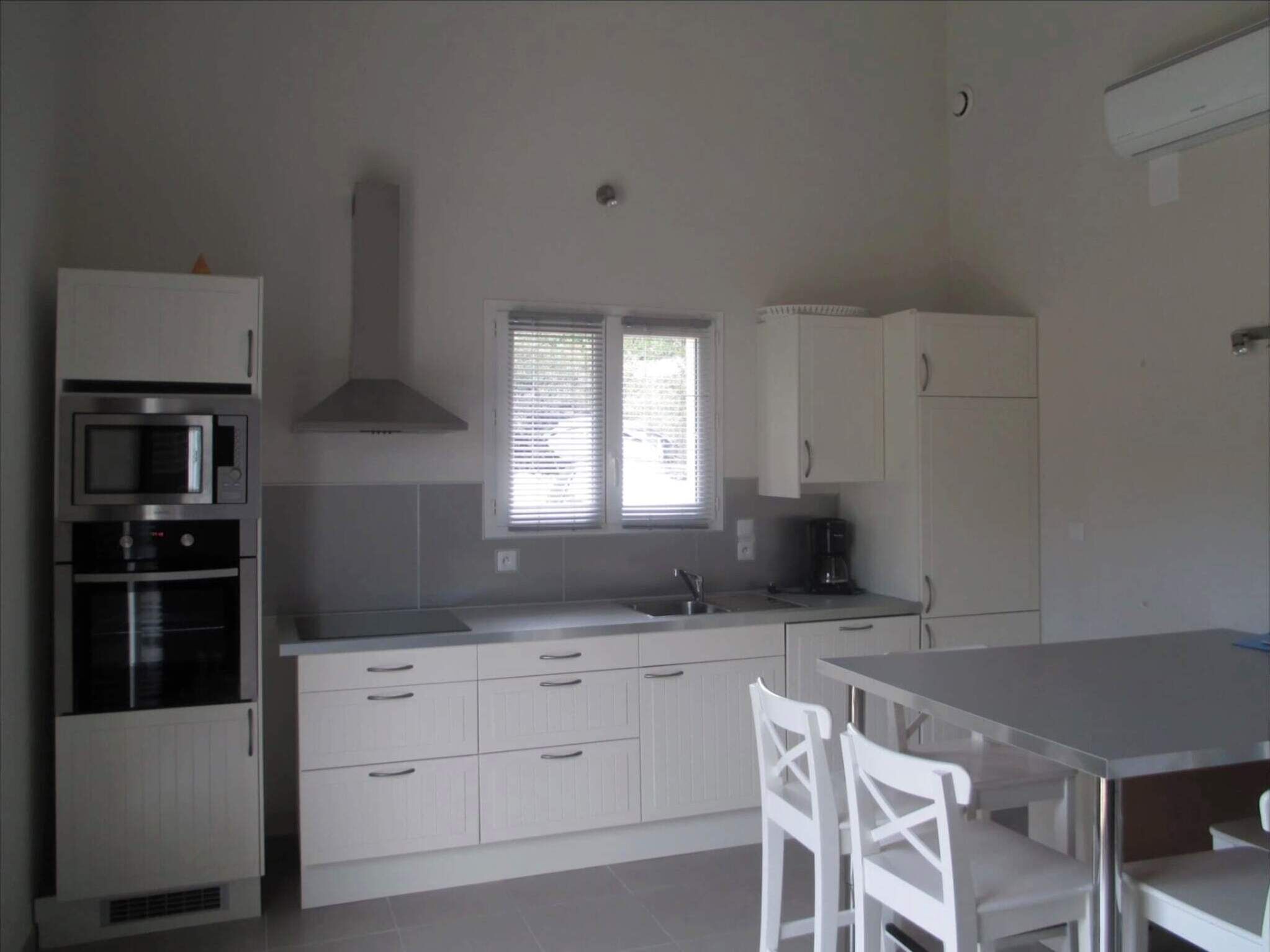 A kitchen with white cabinets, a microwave, an oven, and a coffee maker.