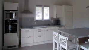 A kitchen with white cabinets, a microwave, an oven, and a coffee maker. - Gîte l'Amandier (Vogüé)