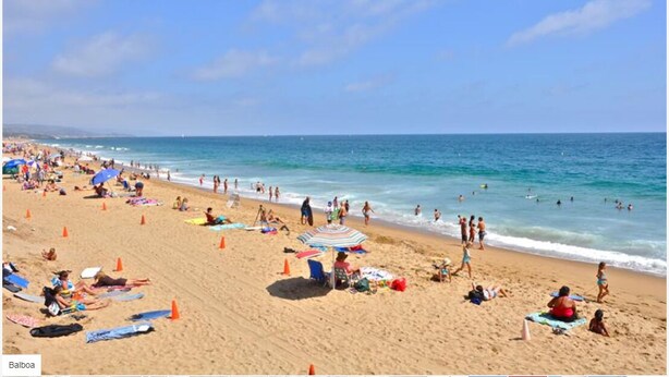 A crowded beach with people sunbathing and swimming, and a clear blue sky. - Charming Newport Beach Home (Newport Beach)