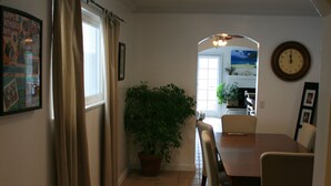 A dining area with a wooden table and chairs, a potted plant, and a clock on the wall. - Charming Newport Beach Home (Newport Beach)