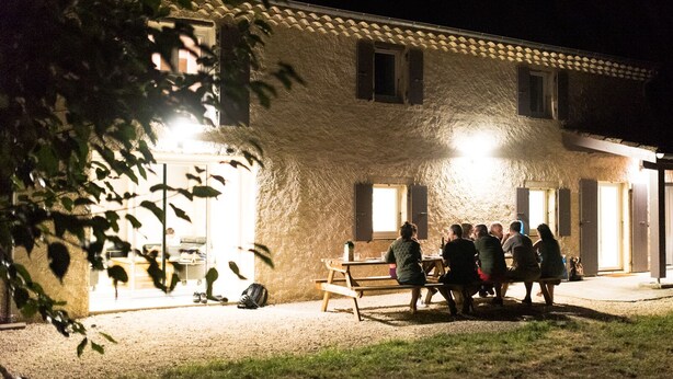 A building with a rustic exterior, a wooden bench in front, and a group of people gathered outside. - In nature, 3 bedroom house sleeps 8-10, totally renovated in 2019 (Aouste-sur-Sye)