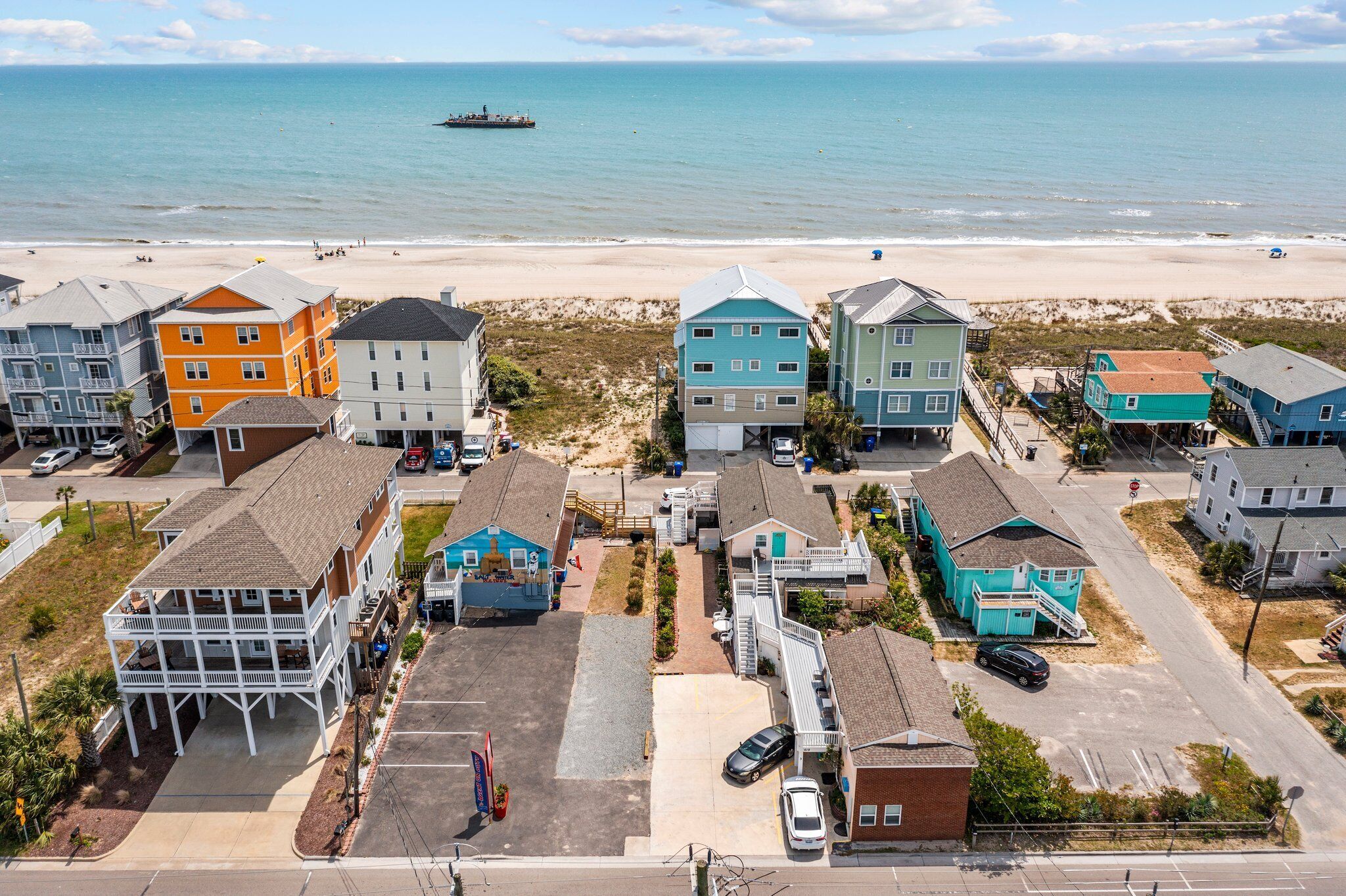 Une zone résidentielle côtière avec des maisons, une plage et un bateau visible au loin.
