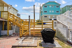 A residential area with a wooden gate, a barbecue grill, and houses with balconies.