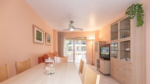 Un espace repas comprenant une longue table, des chaises, un ventilateur de plafond et un téléviseur.