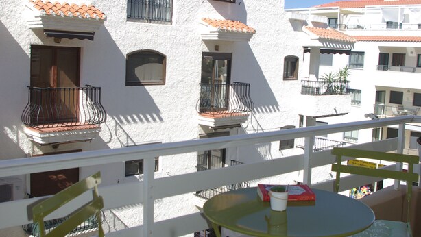 A white building with multiple balconies, a round table with chairs, and a small plant in the foreground. - Central apartment in Moraira (Moraira)
