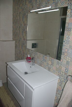 Une salle de bain avec un lavabo blanc, un miroir et des carreaux décoratifs sur les murs.
