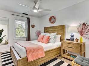 Een slaapkamer met een houten bed, een nachtkastje met een lamp, een spiegel en een raam met zonwering.