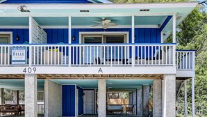 A two-story building with a blue exterior, a balcony with white railings, and a sign indicating pool access. - Heated Pool Access | 5*Clean | Flex Cancelation (Tybee Island)