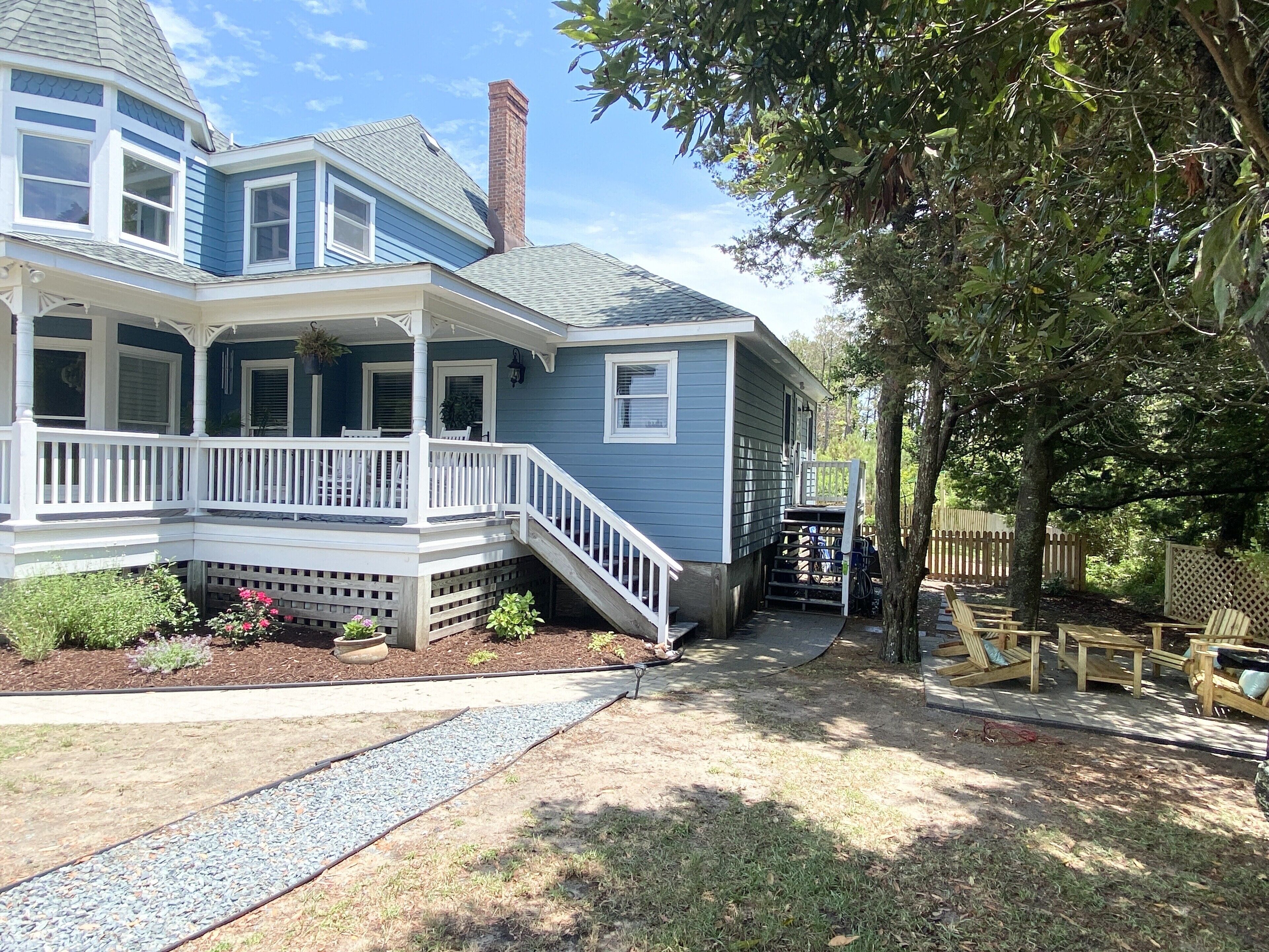 A two-story house with a porch, a chimney, and a fenced yard.