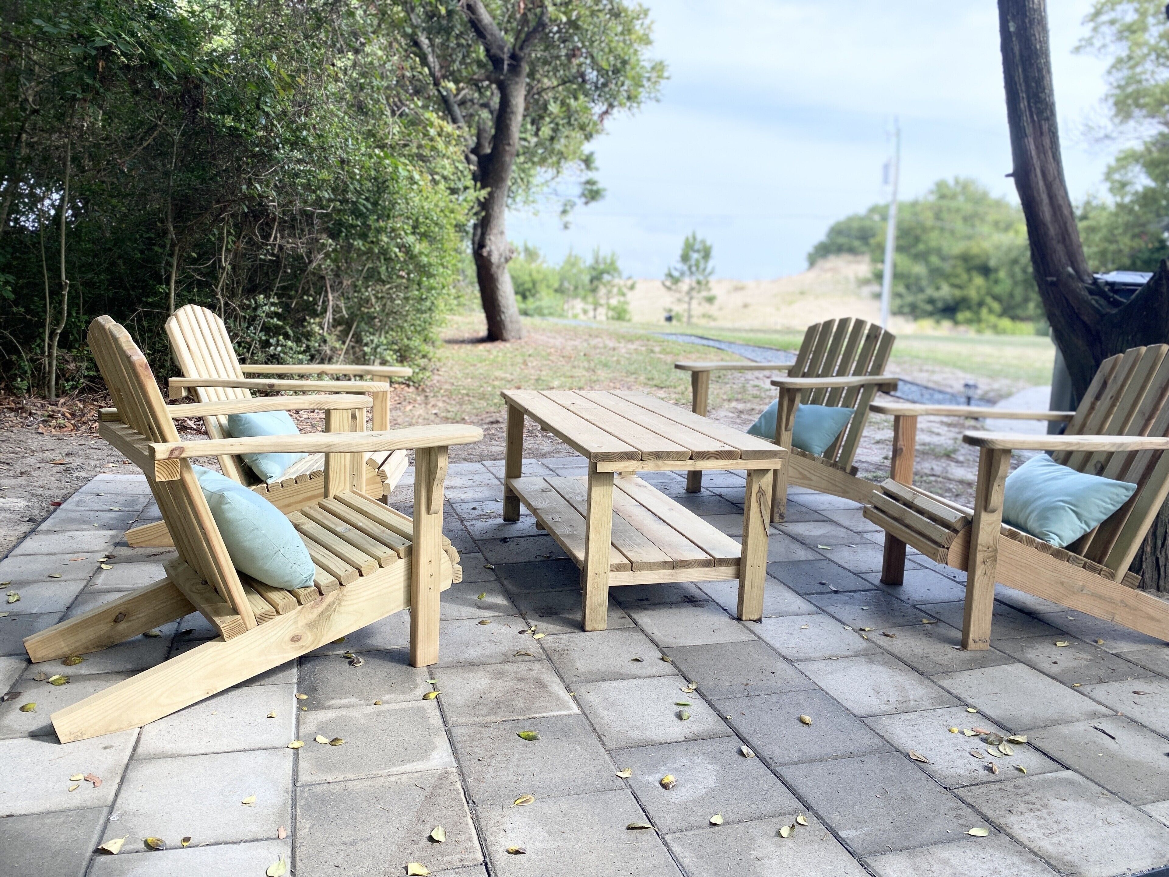 A wooden outdoor seating area with benches and a table, surrounded by trees and a view of the landscape.