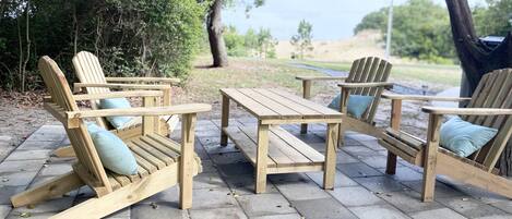 A wooden outdoor seating area with benches and a table, surrounded by trees and a view of the landscape.
