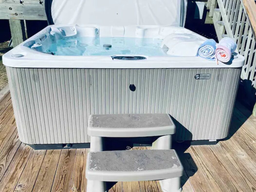 Un jacuzzi con un escalón y un deck de madera alrededor.