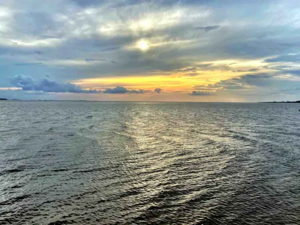 A body of water reflecting sunlight with a cloudy sky above.