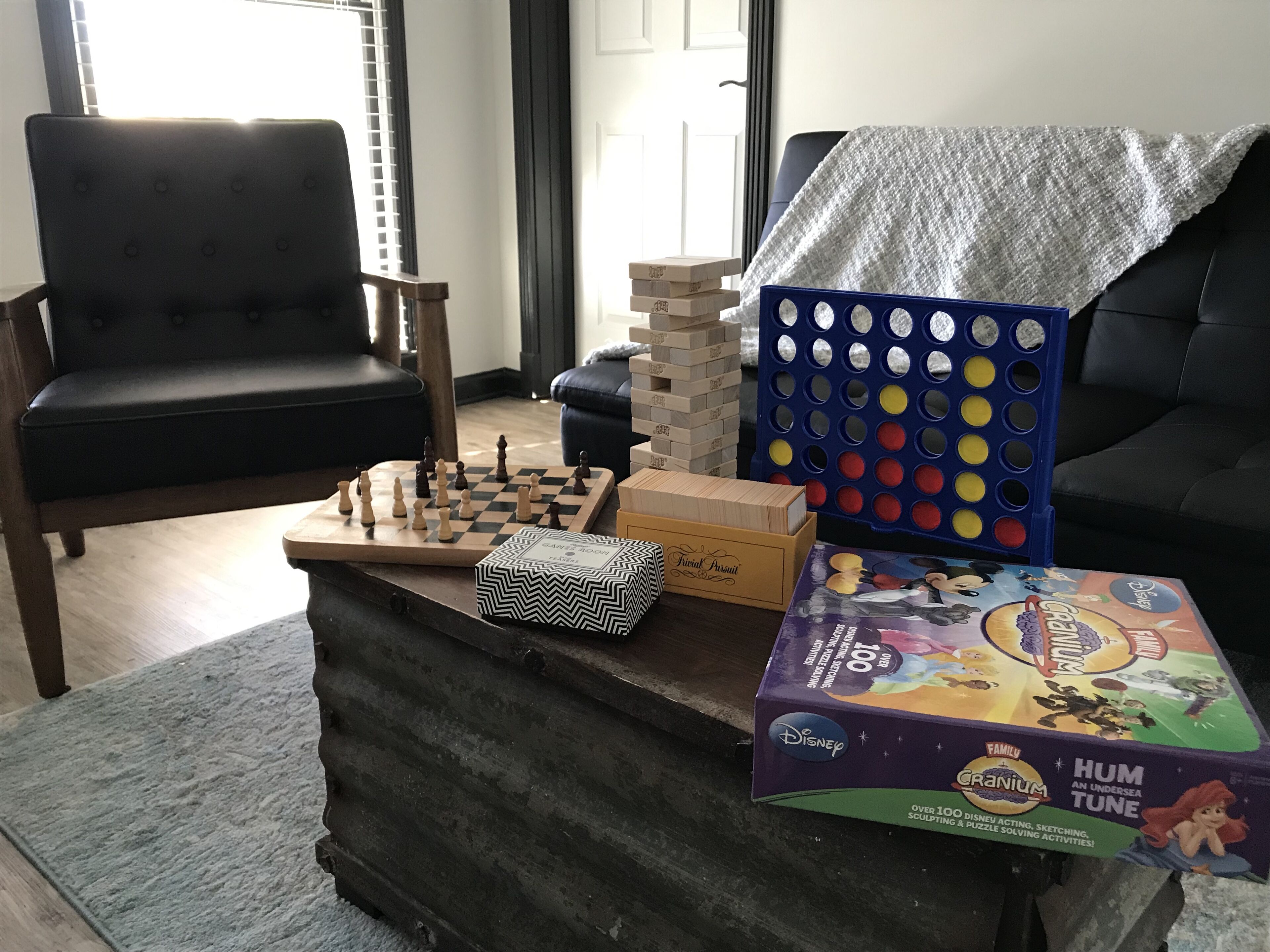 A living room with a chessboard, a jigsaw puzzle, and a box of Disney-themed toys.