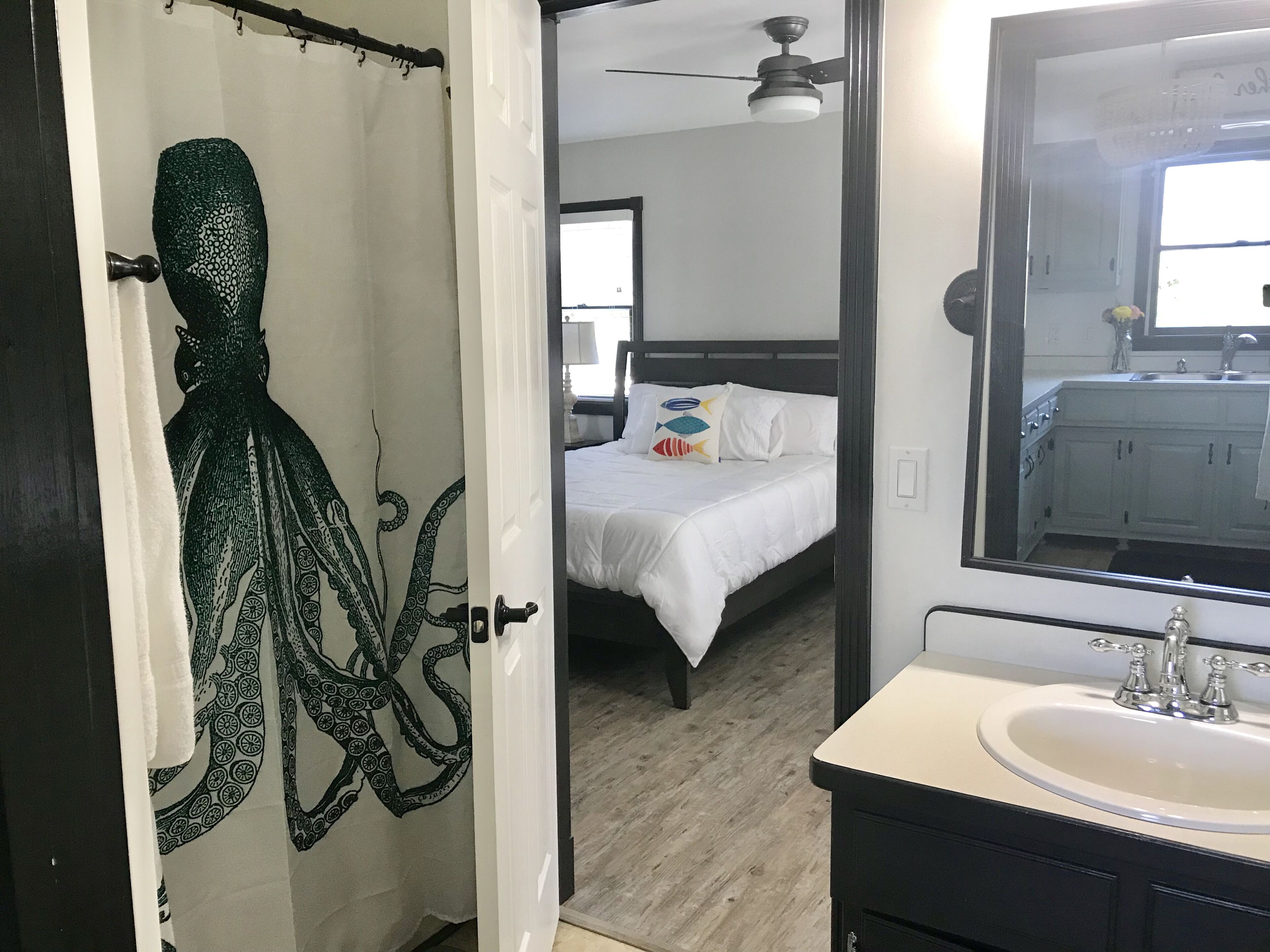 A bedroom with a bed, a bathroom with a sink, and a shower curtain with an octopus design.