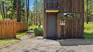 Una cabaña de madera con puerta y ventanas, rodeada de un bosque.