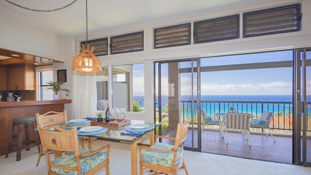 A dining area with a view of the ocean, a bar, and a balcony with outdoor seating.