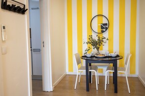 A dining area with a black table, white chairs, and a yellow and white striped wall.