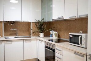 A modern kitchen with white cabinets, a stainless steel sink, a microwave, and a coffee maker. - Comfortable apartment with river view and AC, fully equipped, very close to the center of Lisbon in the traditional Alfama district. (Lisboa ciudad)