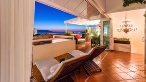 A modern outdoor lounge area with a view of the sea and a sunset.