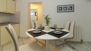 Una cuina moderna amb zona de menjador. Inclou una taula rodona amb caires, una planta en test i un quadre amb marc a la paret.