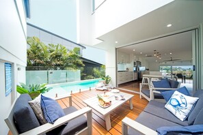 Ein moderner Außenbereich mit Pool, Sitzgelegenheiten und Blick auf die Küche.