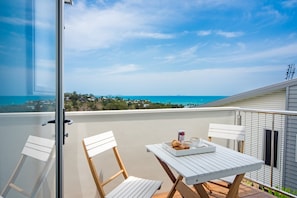 Ein Balkon mit Tisch für zwei Personen, mit Blick auf die Küste.