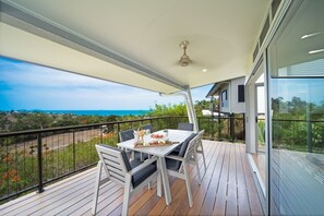 Un balcón con mesa lista para comer, con vistas a un paisaje costero.