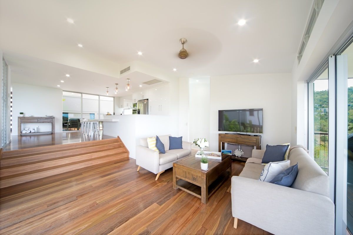A spacious living room with a wooden floor, a sofa set, a coffee table, and a television.