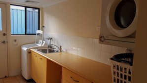 Eine kleine Küche mit Waschmaschine, Spüle und Fenster.