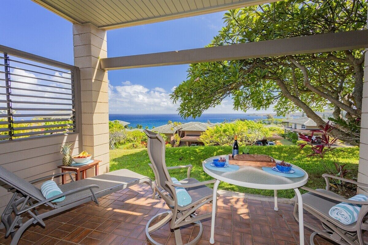 Une terrasse couverte avec vue sur l’océan, une table avec des chaises et un fauteuil de relaxation.