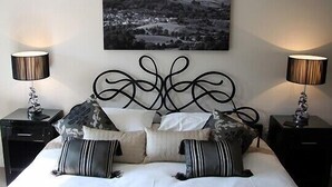Una camera da letto con un letto, due comodini con lampade e un dipinto raffigurante un paesaggio.