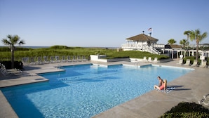 A swimming pool with lounge chairs and a building with an American flag. - Lodge Villa 1 Bedroom in a 57 Acre Resort + Official On-Site Rental Privileges (Myrtle Beach)