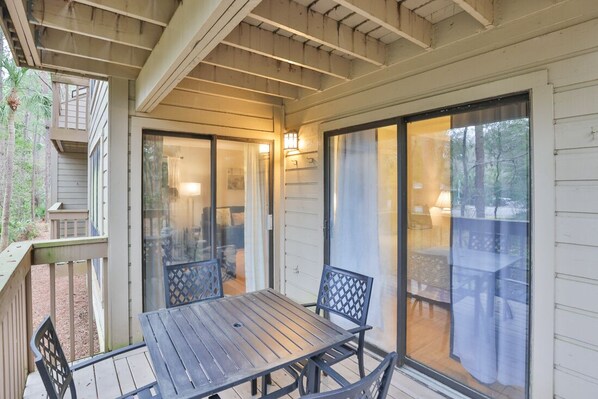 A covered patio with a table and chairs, sliding glass doors, and a wooden deck.