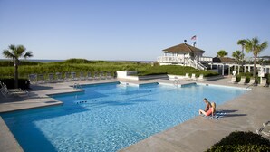A swimming pool with lounge chairs and a building with an American flag.