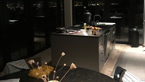 A modern kitchen with a central island, dark cabinetry, and a dining area with a table set for two. - French stonehouse with fantastic views (Théoule-sur-Mer)