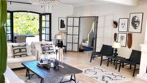 A spacious living room with a large chandelier, a sofa set, a coffee table, and a dining area. - French stonehouse with fantastic views (Théoule-sur-Mer)