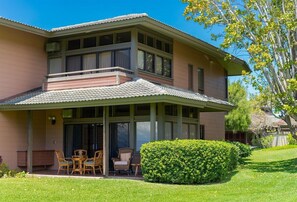 Une maison à deux étages dotée d’un patio couvert, de grandes fenêtres et d’une pelouse bien entretenue.