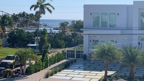 A modern building with large windows, a paved driveway, and a view of the sea.