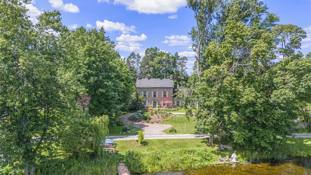 A riverside property with a dock, a house, and lush greenery.