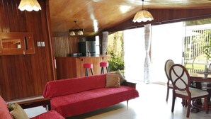 Un salon chaleureux avec un canapé rouge, un plafond en bois et une table à manger avec des chaises.
